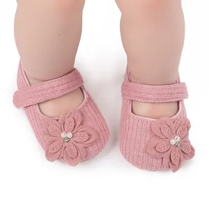 Primo piano di scarpine da neonato in maglia rosa con decorazione floreale di perle.