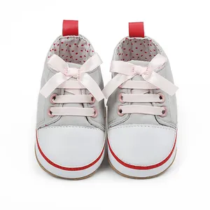 Close-up of grey baby girl walking shoes with pink ribbon bow for 0-1 year olds.