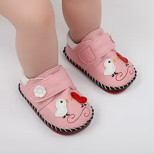 Primer plano de zapatos antideslizantes rosa para bebé con bordado de pájaro de dibujos