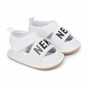 Detailed view of white baby summer sandals with black letter print and velcro strap.