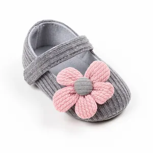 Detail view of pink fabric flower on grey knitted infant princess walking shoe