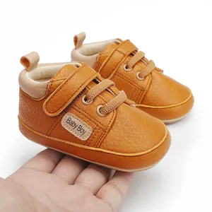 Detailed macro view of brown faux leather baby walking shoes with Baby Boy patch.