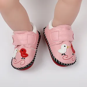Primer plano de los zapatos rosas para bebé con patitos y suelas cosidas a mano