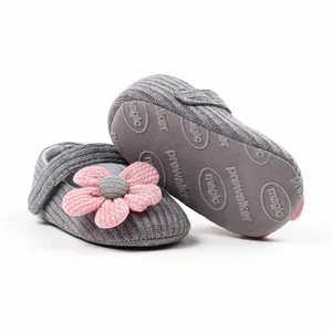 Close-up of soft grey knitted infant walker shoes with a large pink flower ornament.