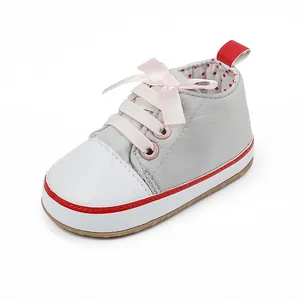 Close-up of grey baby girl walking shoe with pink ribbon laces and white toe cap