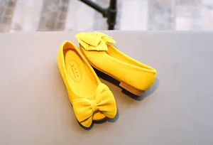 Detailansicht der gelben Samttextur und der großen Schleife an Prinzessinnen-Kinderschuhen