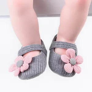 Close-up macro shot of grey knitted baby walker shoes with decorative pink flowers for girls