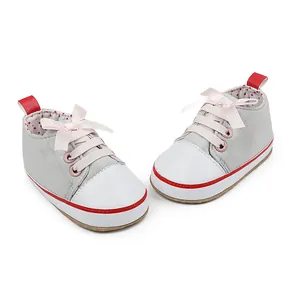 Detailed view of gray infant soft sole walking shoes with cute pink ribbon laces