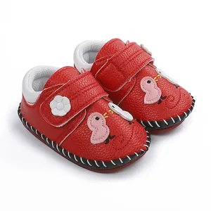 Detalle de zapatos rojos para bebé con dibujos animados y costuras hechas a mano.