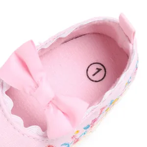 Detailopname van roze baby loopschoentje voor meisjes met borduursel en strikje