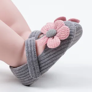 Close-up of grey knitted baby shoes with pink flower decoration for toddlers