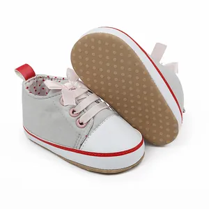 Detailed view of grey baby girl walking shoes with anti-slip dotted sole and pink bow