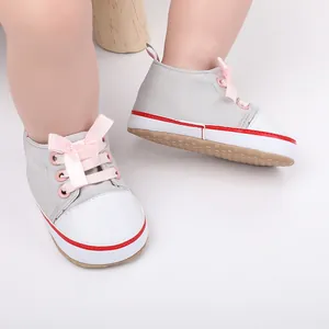 Close-up view of grey baby girl walking shoes with pink ribbon bows and white toe caps.