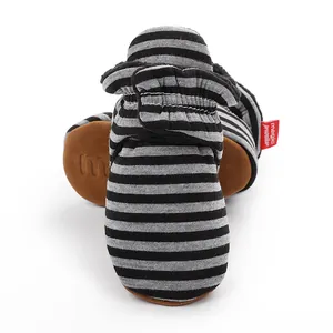 Gros plan de chaussons rayés pour bébé avec étiquette rouge et semelles marron