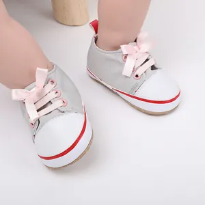 Close-up view of grey canvas baby walking shoes with sweet pink ribbon bow laces