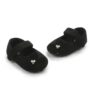 Dettaglio ravvicinato di scarpe da principessa nere per neonata con fiori e perle eleganti