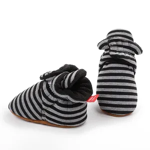 Détail de bottes d'hiver rayées pour bébé avec doublure polaire noire et grise épaisse.