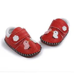 Primer plano de zapatos rojos para bebé con bordado de pájaro y cierre de velcro flor