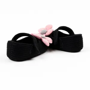 Close-up of black knit baby walker shoes featuring pink crocheted flower details