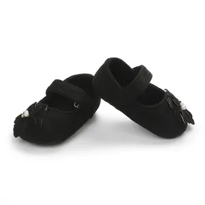 Dettaglio di scarpe Mary Jane nere per neonato con fiore di perle e suola morbida.