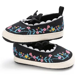 Detailweergave van zwarte geborduurde babyschoentjes met bloemmotieven en strikken.