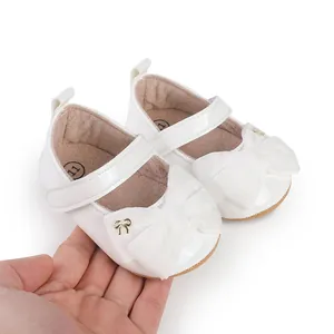 Detalle en primer plano de zapatos blancos de princesa para bebé con un gran lazo