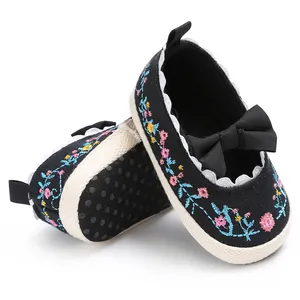 Detailopname van zwarte baby loopschoenen met bloemenborduurwerk en een strikje