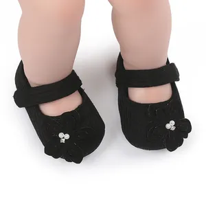 Primo piano di scarpe da principessa nere per neonati con fiore decorativo sui piccoli piedi