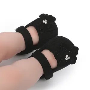 Primo piano di scarpe da principessa nere per neonata con fiori 3D e perle