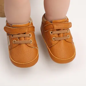 Close-up detail of brown leather baby pre-walker shoes with Velcro strap and laces.