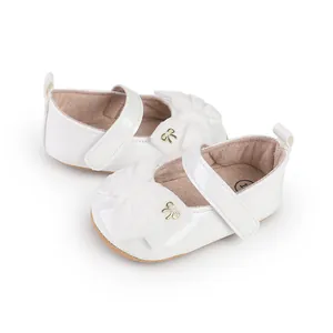 Vista detallada de zapatos blancos de princesa para bebé con lazos y hebillas doradas