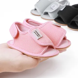 Detailaufnahme von rosa atmungsaktiven Mesh-Babysandalen in der Hand eines Erwachsenen
