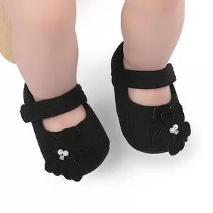 Dettaglio di scarpe da passeggio nere per neonati con fiore 3D decorativo e perle bianche