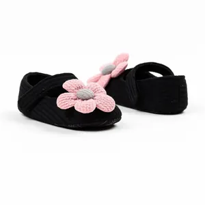 Detailed view of black knit infant pre-walker shoes with pink floral crochet decoration.