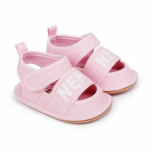 Close-up of pink infant walking sandals with white NEK letters and hook-and-loop straps