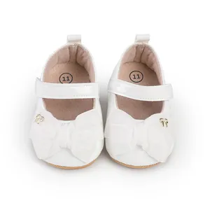 Vista detallada de zapatos de princesa blancos para bebé con lazo grande de tela