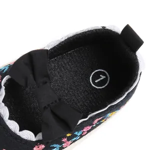 Detailweergave van zwarte geborduurde baby prinsessenschoen met een strikje
