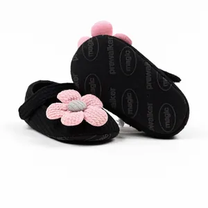 Close-up of black knit baby walker shoes with pink 3D flower and anti-slip sole detail