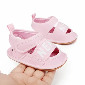 Detailed macro view of soft pink baby summer walking sandals held by hand for scale
