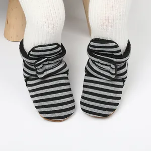 Gros plan sur des chaussons bébé rayés noir et gris, bottines d'apprentissage chaudes