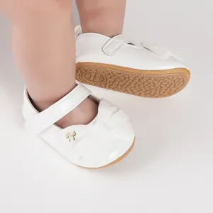 Vista detallada de zapatos de princesa blancos para bebé con lazo de terciopelo y suela goma