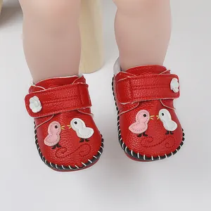 Detalle de zapatos rojos para bebé con bordado de pájaros y suela de goma