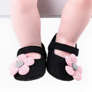Close-up of black baby walker shoes with pink knit flower embellishments