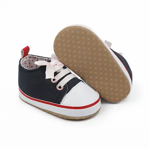 Detail of navy blue baby walking shoes with pink ribbon laces and non-slip sole.