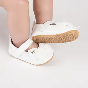 Primer plano de zapatos de princesa para bebé en charol blanco con lazo