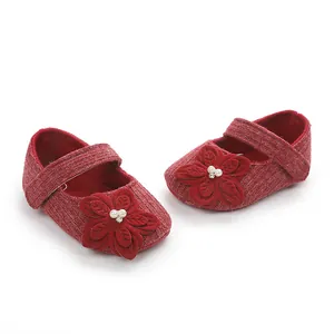 Dettaglio scarpe da principessa per neonata in maglia rossa con fiori decorativi e perle