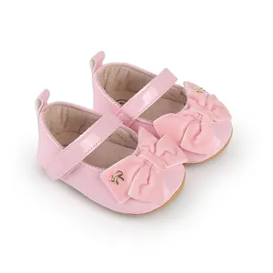 Primer plano de elegantes zapatos de princesa rosa para bebé con grandes lazos de terciopelo.