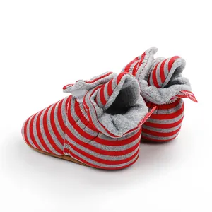 Gros plan de bottines d'hiver rayées rouges et grises pour bébé avec doublure polaire