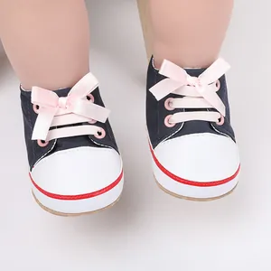 Close-up detail of navy blue infant walking shoes featuring decorative pink ribbon bow laces.