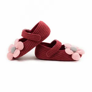 Detailed view of red knitted baby girl princess shoes with pink floral decoration